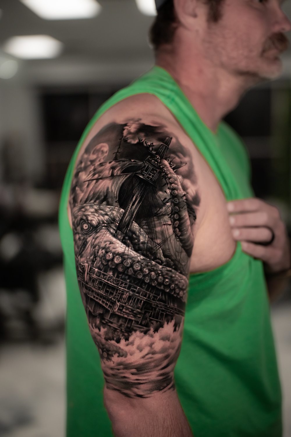 Black and grey kraken and ship cover-up tattoo on an upper arm