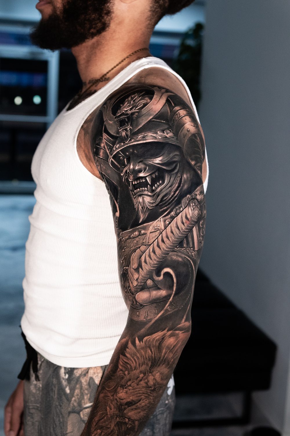 Black and grey samurai mask cover-up tattoo on an upper arm