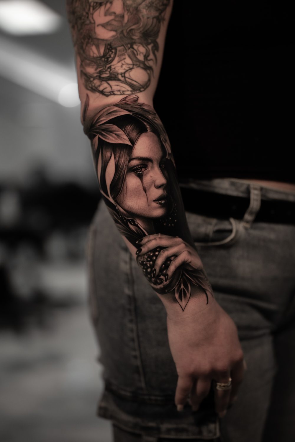 Black and grey portrait tattoo of a woman with leaves on a forearm