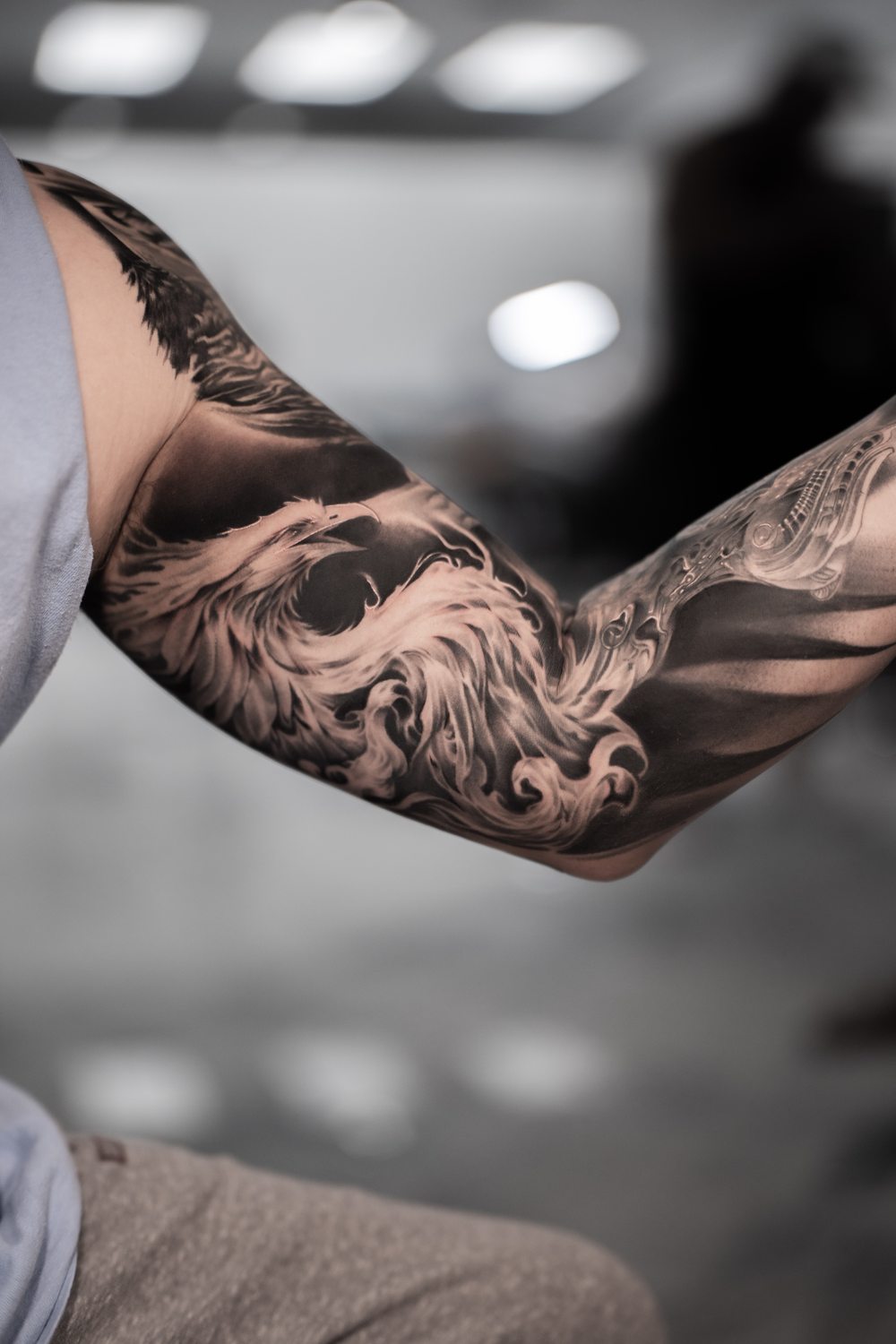 Black and grey phoenix sleeve tattoo on an inner arm
